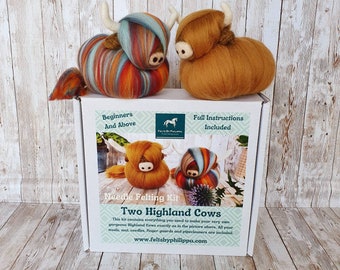 May include: A needle felting kit to make two Highland cows. The kit includes all the materials needed, including wool, needles, and instructions. The kit is shown with two finished Highland cows, one with a brown and orange color scheme and the other with a blue, orange, and red color scheme.