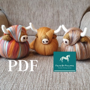 Puede incluir: Tres adornos de vaca Highland de fieltro hechos a mano en diferentes combinaciones de colores. Las vacas están sentadas en un sofá marrón con un cartel azul verdoso que dice "Felts by Philippa Noodle Felting Artist" en texto blanco.