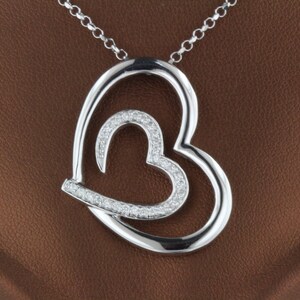 May include: A silver necklace with a double heart pendant. The smaller heart is set with small diamonds.
