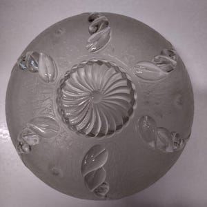 May include: A white frosted glass ceiling light fixture with a decorative floral design. The fixture has a central swirl pattern and a frosted finish.