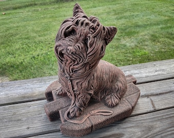 May include: A brown ceramic statue of a Yorkshire Terrier dog sitting on a base with a leash. The dog is looking up and has a detailed, realistic appearance.