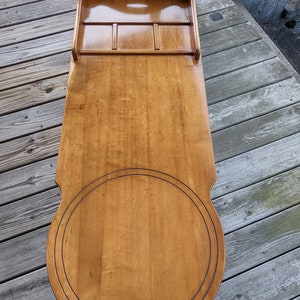 May include: A wooden table with a round top and a built-in tray. The table is made of light wood and has a natural finish.