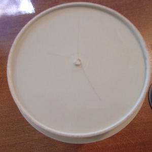 K&ouml;nnte beinhalten: Ein wei&szlig;er Plastikdeckel mit einem kleinen Loch in der Mitte. Der Deckel hat eine leichte Vertiefung in der Mitte.