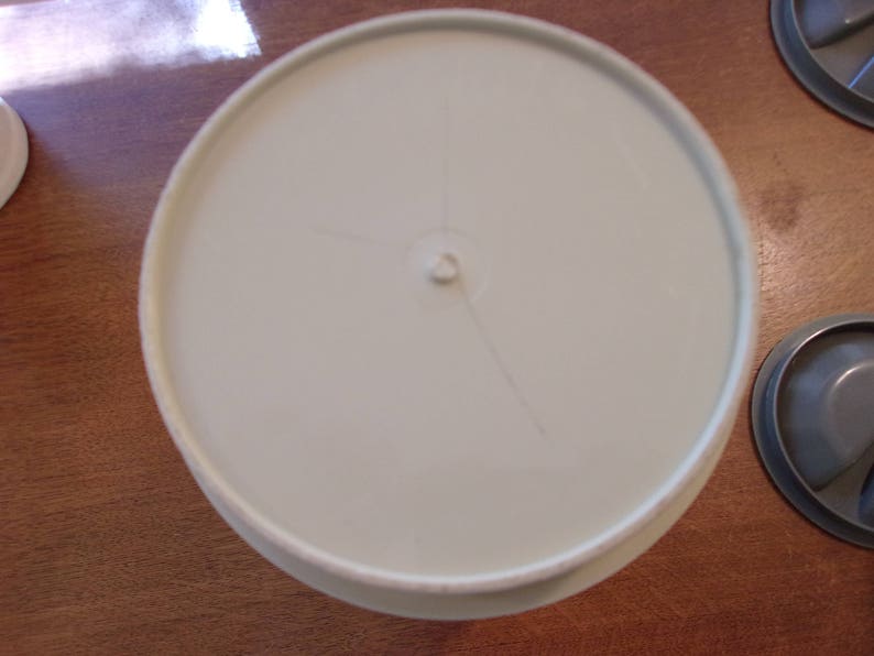 K&ouml;nnte beinhalten: Ein wei&szlig;er Plastikdeckel mit einem kleinen Loch in der Mitte. Der Deckel hat eine leichte Vertiefung in der Mitte.