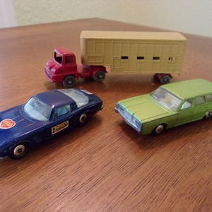 Könnte beinhalten: Drei Spielzeugautos, ein blauer Sportwagen, ein grüner Kombi und ein roter LKW, der einen beigefarbenen Anhänger zieht. Das blaue Auto hat einen Aufkleber mit der Aufschrift "Drivers".