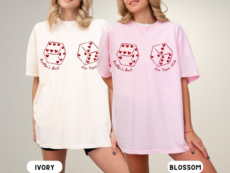 May include: Ivory and blossom-colored t-shirts with a dice graphic. Each die features heart-shaped pips and the text "Kaitlyn's Bach Las Vegas 2024" in red. The shirts are a casual, oversized fit.