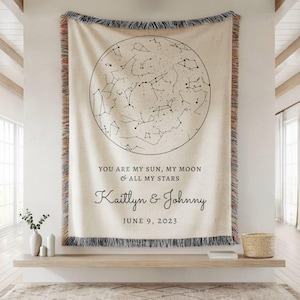 May include: A cream-colored woven throw blanket featuring a black circular star map graphic. The text reads: YOU ARE MY SUN, MY MOON & ALL MY STARS, Kaitlyn & Johnny, JUNE 9, 2023. The blanket has a fringed edge with multicolored threads.