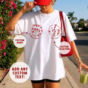 May include: White t-shirt with red dice graphic and text. The dice have heart-shaped pips. Text includes "Kaitlyn's Back" and "Las Vegas 2023". The shirt also has prompts for custom name, location, and text.