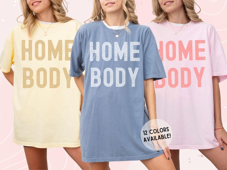 May include: Three oversized t-shirts with the text "HOME BODY" in different colors. The shirts are in yellow, blue, and pink.