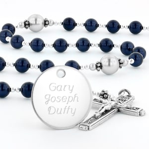 May include: A silver rosary with dark blue beads and a silver pendant with the name "Gary Joseph Duffy" engraved on it. The rosary also has a silver crucifix.