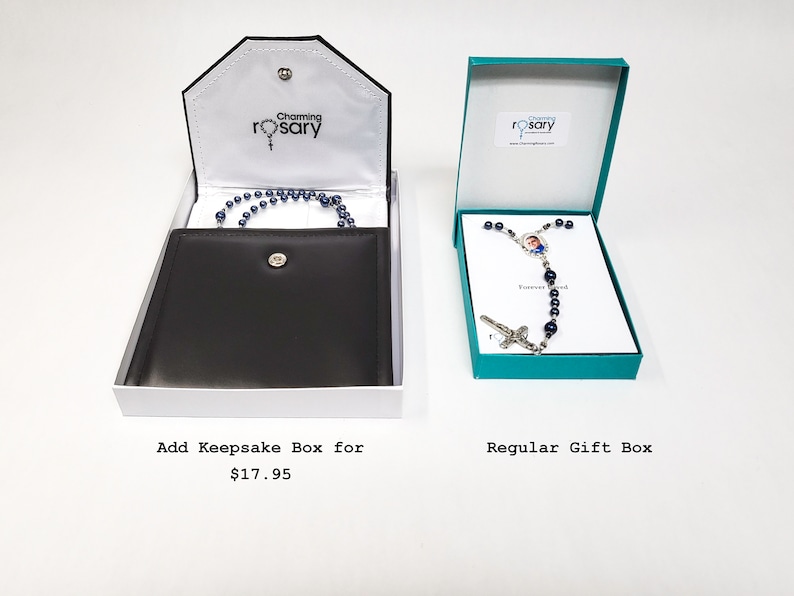 May include: Two gift boxes for a rosary. The box on the left is a keepsake box with a black velvet interior. The box on the right is a regular gift box with a teal blue exterior. Both boxes have the text "Charming Rosary" on them.