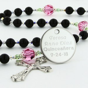 May include: Black and silver rosary beads with a pink crystal accent and a silver charm with the text "Teresa Anne Diaz Quincea&ntilde;era 9-24-18".