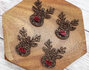 May include: Four glittery reindeer head ornaments with brown and gold glitter and red noses are arranged on a wooden, hexagonal tray. The reindeer have detailed antlers and are suitable for holiday crafts or decorations.