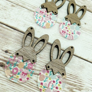 May include: Four wooden bunny head ornaments with floral patterned resin Easter eggs. The bunny heads are brown and the eggs are clear with a pink, yellow, and blue floral pattern.