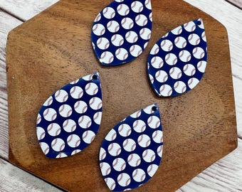 May include: Four baseball-themed teardrop earrings. Each earring features a navy blue background with a pattern of white baseballs. The baseballs have red stitching details. The earrings are displayed on a wooden surface.