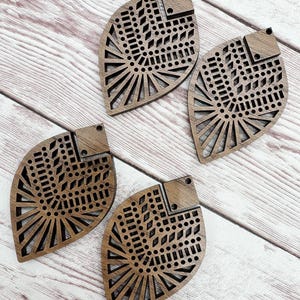May include: Four brown wooden leaf-shaped earrings with intricate laser-cut geometric designs. The earrings have a hole at the top for attaching earring hooks.
