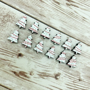 May include: Twelve wooden Christmas tree ornaments with a white background and red and green polka dots.