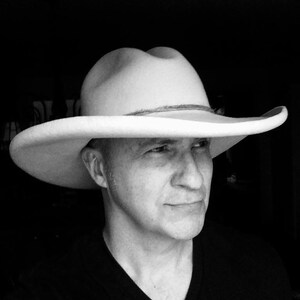 Puede incluir: Un hombre con un sombrero de vaquero blanco y una camisa negra.