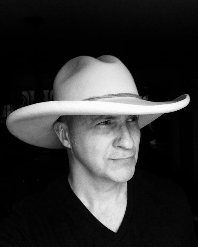 Puede incluir: Un hombre con un sombrero de vaquero blanco y una camisa negra.