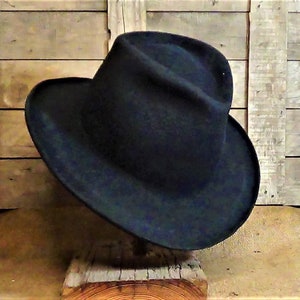 Puede incluir: Un sombrero fedora azul oscuro de ala ancha. El sombrero est&aacute; hecho de fieltro y tiene un estilo cl&aacute;sico.