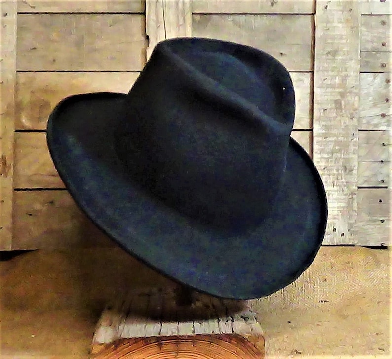 Puede incluir: Un sombrero fedora azul oscuro de ala ancha. El sombrero est&aacute; hecho de fieltro y tiene un estilo cl&aacute;sico.