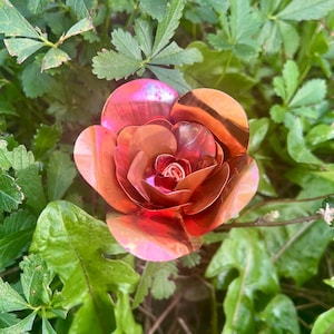 May include: A copper rose with a shiny, iridescent finish. The rose is made of metal and has a realistic appearance.