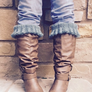 May include: Brown knee-high boots with a buckle strap and a pair of teal knitted leg warmers.