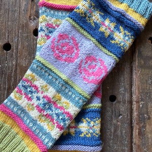 May include: A pair of colorful knitted leg warmers with a geometric pattern. The leg warmers are made of a soft, textured yarn and feature a variety of colors, including blue, green, yellow, pink, and white.