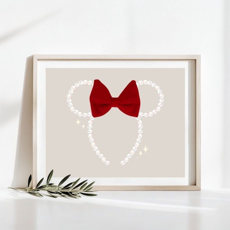 May include: A framed print featuring a Minnie Mouse-inspired design. The artwork showcases a red bow and pearl-like beads arranged in the shape of mouse ears. Sparkling accents are included on a neutral background.