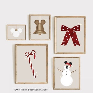 Op de afbeelding: Vijf ingelijste prints met een kerstthema. De prints tonen een Mickey Mouse-ornament, een bel, een rode strik met witte hartjes, een zuurstok en een sneeuwpop met een Mickey Mouse-hoed. De tekst "EACH PRINT SOLD SEPARATELY" staat onderaan.