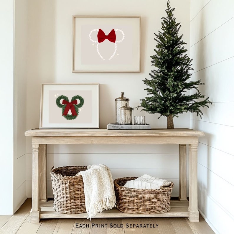 May include: Two framed prints with a Minnie Mouse theme, one with a red bow and pearl ears, the other with a green wreath and red bow. A small Christmas tree and decorative items sit on a wooden console table with two wicker baskets.