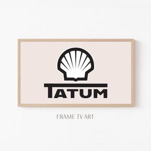 May include: A framed print featuring a black and white seashell logo above the word "TATUM" in a bold, sans-serif font. The background is a soft pink, and the frame is a light wood color. The words "FRAME TV ART" are at the bottom.