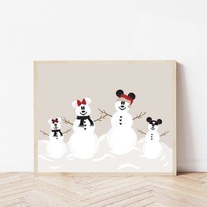 May include: A framed print featuring four snowmen with Mickey Mouse ears, each with a unique scarf or hat. The snowmen are set against a neutral background, creating a festive winter scene. The print is displayed on a wooden floor.