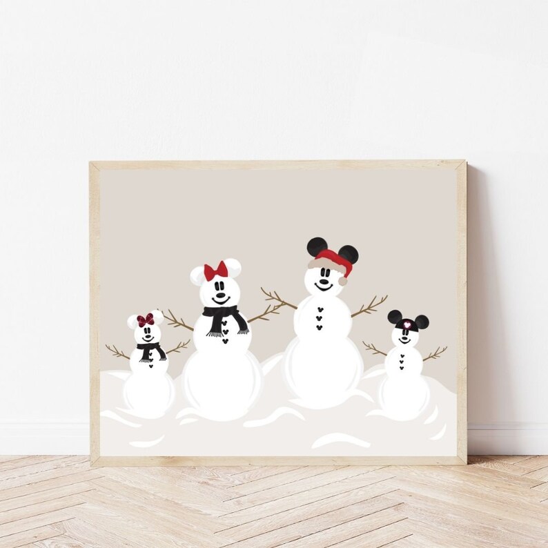 May include: A framed print featuring four snowmen with Mickey Mouse ears, each with a unique scarf or hat. The snowmen are set against a neutral background, creating a festive winter scene. The print is displayed on a wooden floor.