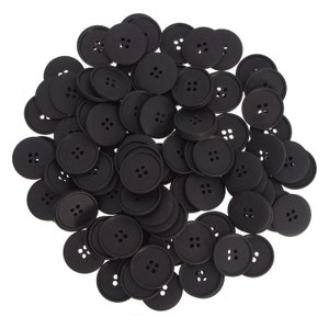 Peut inclure: Un grand tas de boutons en plastique noir avec quatre trous chacun. Les boutons sont tous de la même taille et de la même forme.
