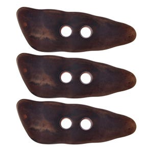 May include: Three dark brown, oblong buttons with two holes each. The buttons have a natural wood grain appearance and are arranged vertically against a white background. These buttons are suitable for sewing projects, crafts, or adding a rustic touch to garments.