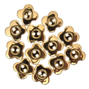 May include: A group of 12 gold-coloured flower-shaped buttons with two holes each.
