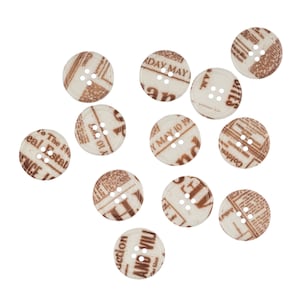 Pode incluir: Uma coleção de 12 botões brancos com designs de impressão de jornal marrom. Os botões têm quatro furos cada um e estão espalhados em um fundo branco.