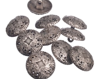 May include: A set of nine silver-toned buttons with intricate floral designs. The buttons are round and have a raised center with a hole for sewing.