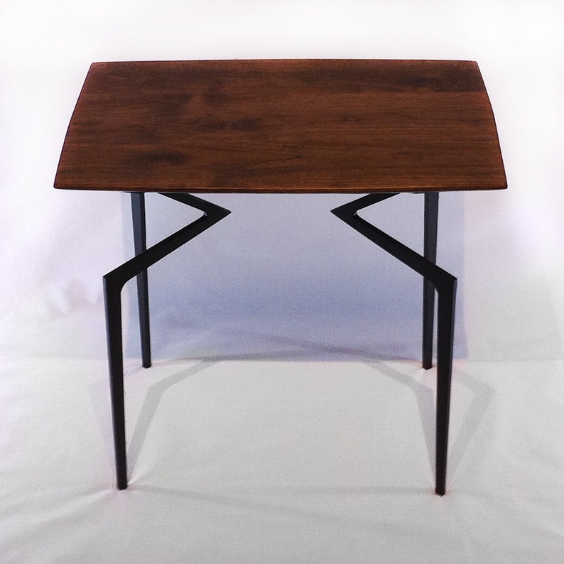 May include: A dark brown wooden table with a rectangular top and black metal legs. The legs are angled and form a geometric pattern.