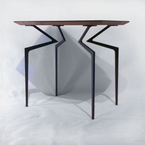May include: A modern, minimalist table with a dark wood top and black metal legs. The legs are angled and create a unique, geometric design.