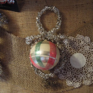 May include: A vintage Christmas ornament with a white, red, and green striped design. The ornament is made of glass and has a silver tinsel hanger.