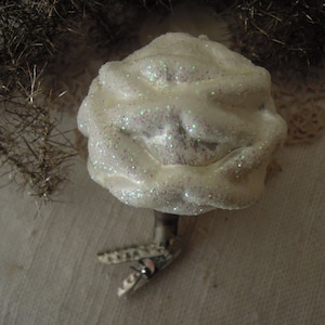 May include: White Christmas tree ornament with a sparkly finish. The ornament is shaped like a tree and has a textured surface.