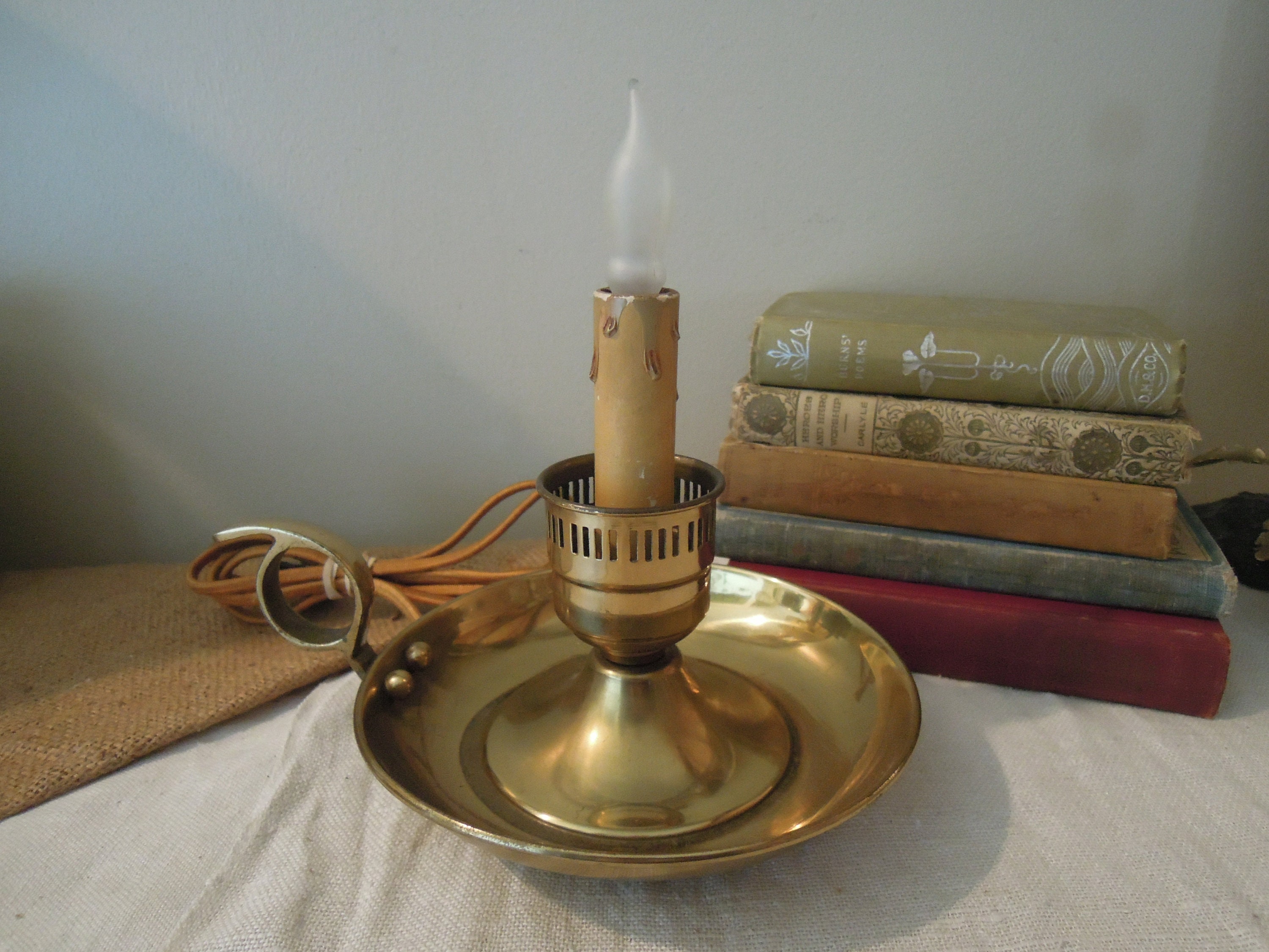 Lot - Four antique brass lighting objects, including a fluid lamp, gimbal  candle holder, square tray chamber stick and push-up round foot