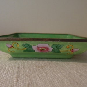 Op de afbeelding: Een vierkante, groene cloisonn&eacute;-schotel met een bloemenmotief. De schotel heeft een gouden rand en is versierd met roze en gele bloemen en groene bladeren.