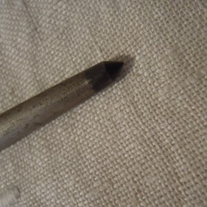 May include: A close-up of the pointed end of a silver metal rod.