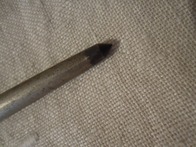 May include: A close-up of the pointed end of a silver metal rod.