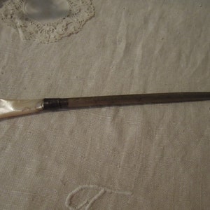 May include: A silver and mother-of-pearl sewing thimble with a pointed end.