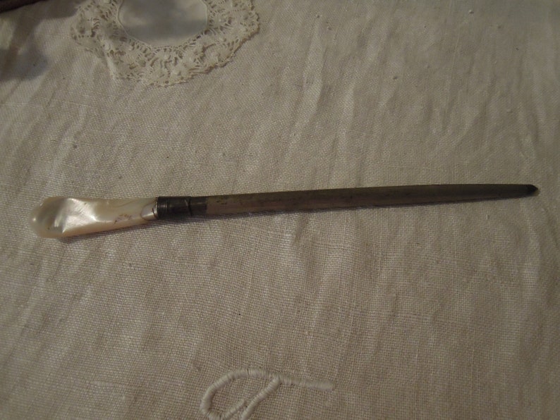 May include: A silver and mother-of-pearl sewing thimble with a pointed end.