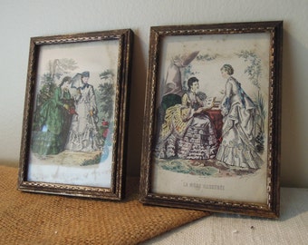 May include: Two framed antique prints of women in 19th century fashion. The prints are in gold frames and feature women in elaborate dresses and hats. The text on the bottom of the right print reads "La Mode Illustree".